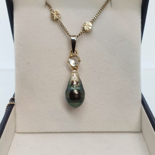 photo of a white gold chain with pendant with diamond and a black pearl.